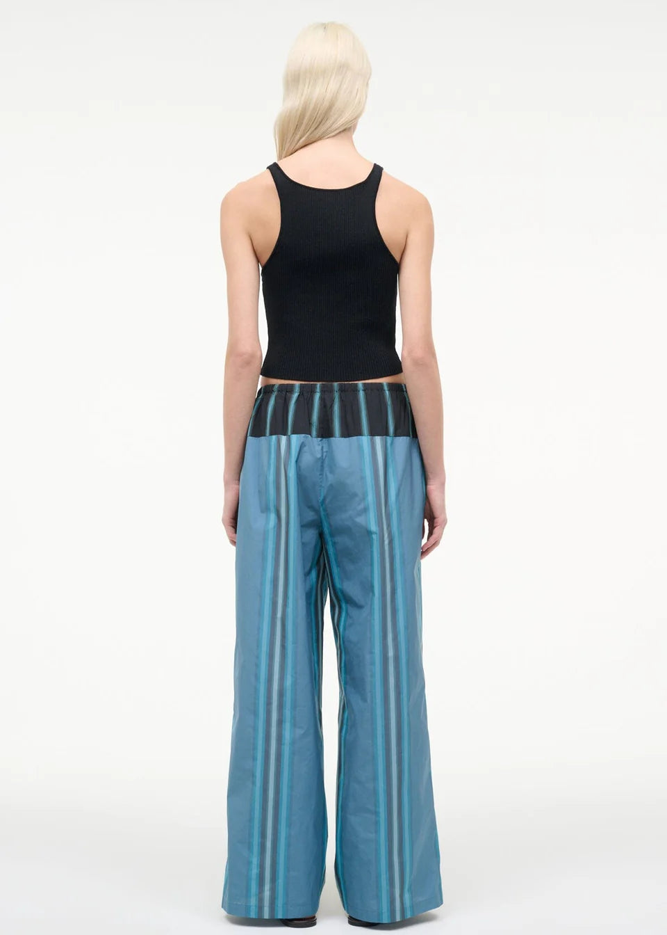 A person seen from behind wears a black ribbed tank top and Mateo Pant wide-leg trousers, featuring blue vertical stripes and a dark contrasting waistband.