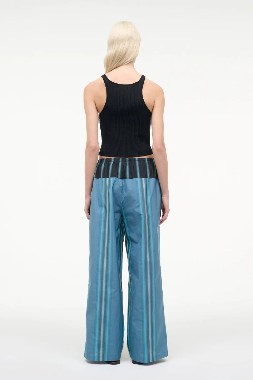A person seen from behind wears a black ribbed tank top and Mateo Pant wide-leg trousers, featuring blue vertical stripes and a dark contrasting waistband.