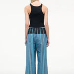A person seen from behind wears a black ribbed tank top and Mateo Pant wide-leg trousers, featuring blue vertical stripes and a dark contrasting waistband.