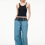 A person wears a black ribbed tank top and Mateo Pant, featuring blue striped fabric and a black drawstring waistband.