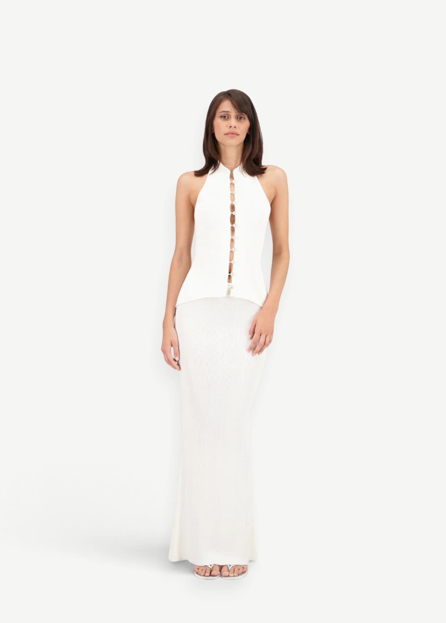 Model wearing a KABE SHOP INC white sleeveless top with front button detail and a matching floor-length maxi skirt.