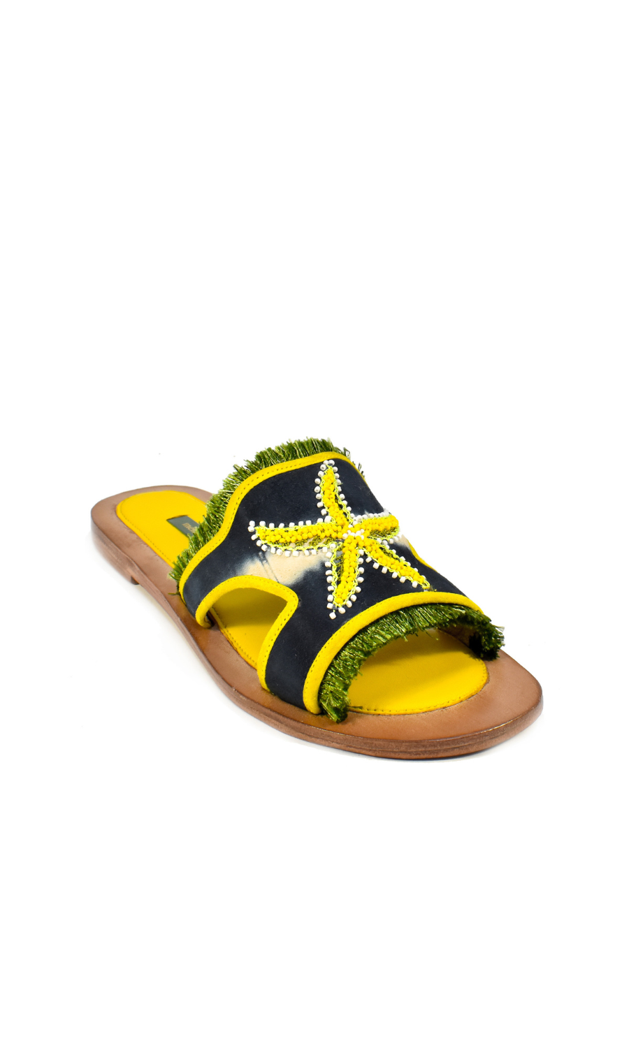 Introducing the Mazu Slide: these hand-embroidered leather sandals feature a brown sole, yellow footbed, and a black strap adorned with a yellow beaded starfish and green fringe accents—making them a stunning example of sustainable footwear.