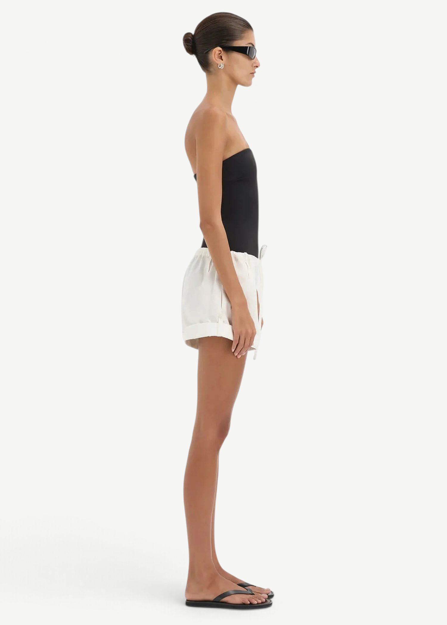 Model wearing KABE SHOP INC white lightweight cotton Charlie Rolled Shorts with a drawstring waist, side profile view