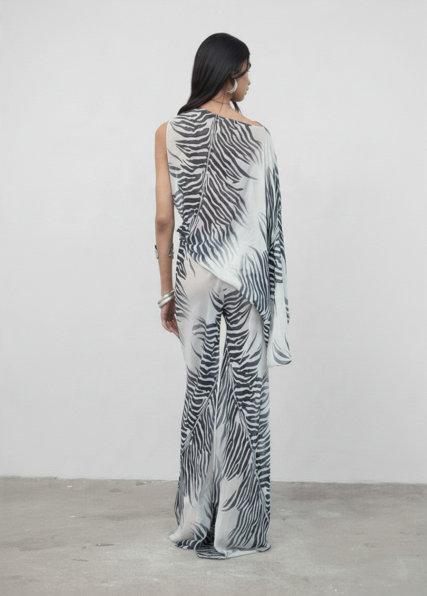 Model wearing KABE SHOP INC Luma Trousers in a floor-length, bias-cut viscose georgette with a black and white zebra print.