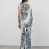 Model wearing KABE SHOP INC Luma Trousers in a floor-length, bias-cut viscose georgette with a black and white zebra print.