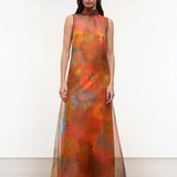 Sleeveless, floor-length Albee Dress with a high mock neck, featuring an abstract orange, red, and yellow floral print in a sheer fabric.
