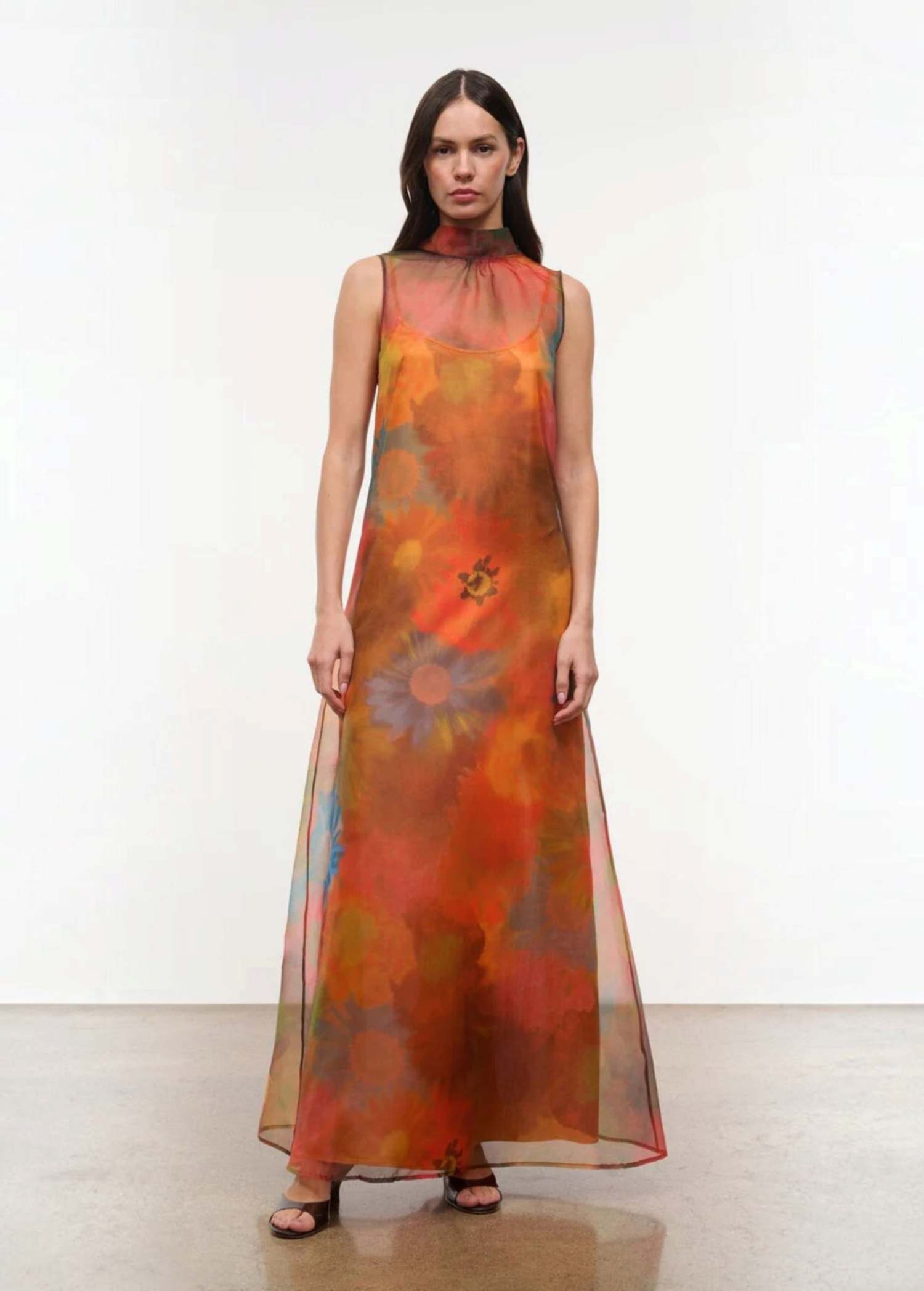 Sleeveless, floor-length Albee Dress with a high mock neck, featuring an abstract orange, red, and yellow floral print in a sheer fabric.