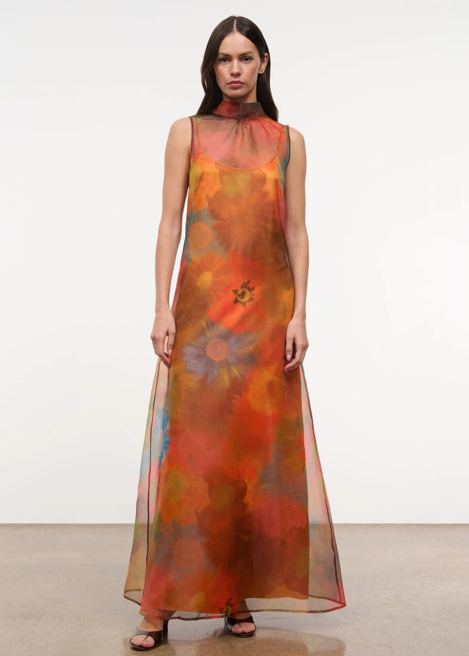 Sleeveless, floor-length Albee Dress with a high mock neck, featuring an abstract orange, red, and yellow floral print in a sheer fabric.
