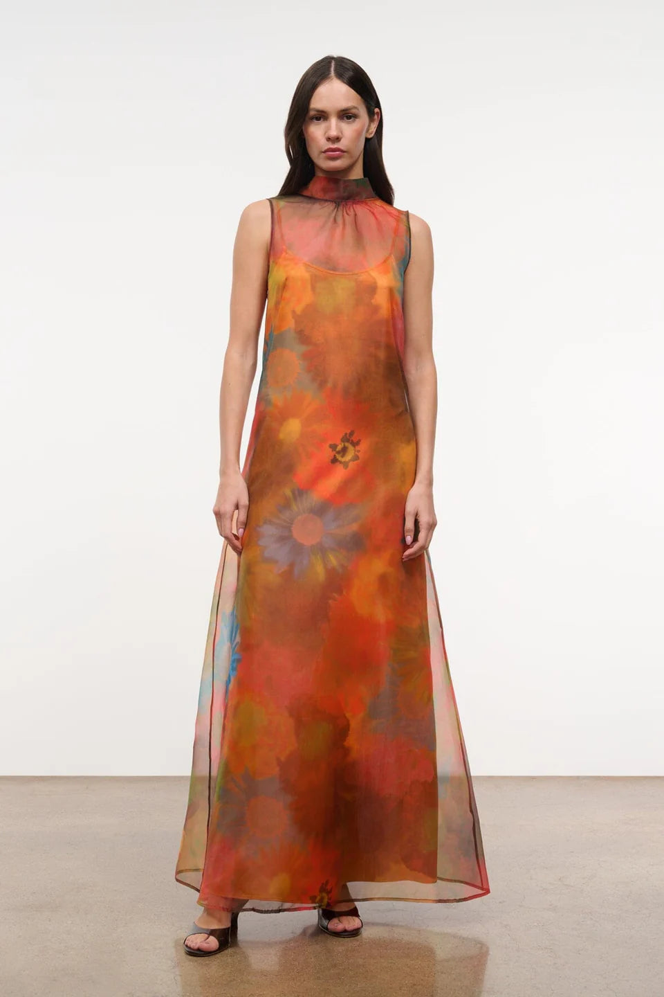 Sleeveless, floor-length Albee Dress with a high mock neck, featuring an abstract orange, red, and yellow floral print in a sheer fabric.