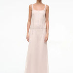 The Greta Dress is an elegant, floor-length, pale pink sleeveless evening dress featuring a scoop neckline and vertical rows of small decorative buttons.