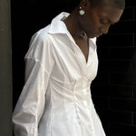 A person wears a white long-sleeved Laced Button Down shirt featuring side corset-style lace-up detailing for a feminine silhouette.