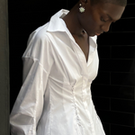 A person wears a white long-sleeved Laced Button Down shirt featuring side corset-style lace-up detailing for a feminine silhouette.