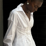 A person wears a white long-sleeved Laced Button Down shirt featuring side corset-style lace-up detailing for a feminine silhouette.