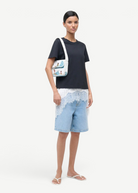 Model wearing KABE SHOP INC Tommy beaded shoulder bag with a playful beach-themed design over a black t-shirt