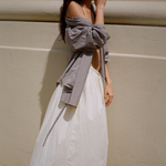 KABE SHOP INC Rhea maxi skirt in cream with an adjustable waistband, styled with a gingham shirt against a wall.