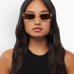 Woman wearing KABE SHOP INC Verve rectangular sunglasses with clear frames and brown lenses against a white background