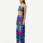 Woman wearing the Alma Set—a colorful blue linen crop top and wide-leg pants ensemble featuring a vibrant abstract floral pattern—standing against a light background, perfect for versatile styling with adaptable accessories.
