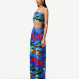 Woman wearing the Alma Set—a colorful blue linen crop top and wide-leg pants ensemble featuring a vibrant abstract floral pattern—standing against a light background, perfect for versatile styling with adaptable accessories.