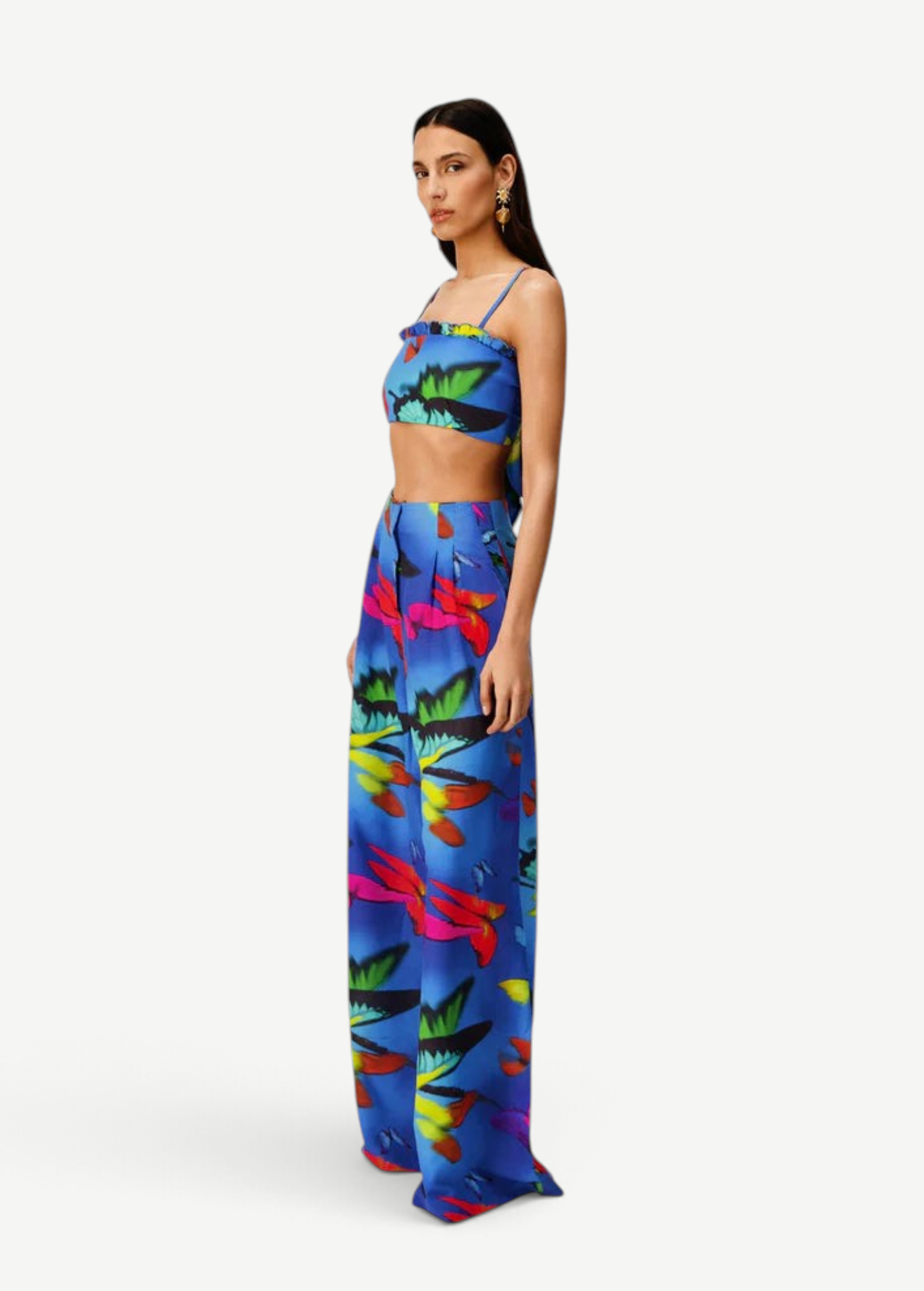 Woman wearing the Alma Set—a colorful blue linen crop top and wide-leg pants ensemble featuring a vibrant abstract floral pattern—standing against a light background, perfect for versatile styling with adaptable accessories.