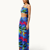 Woman wearing the Alma Set—a colorful blue linen crop top and wide-leg pants ensemble featuring a vibrant abstract floral pattern—standing against a light background, perfect for versatile styling with adaptable accessories.