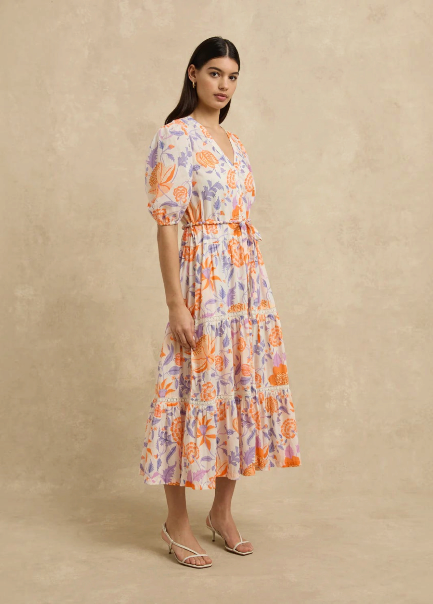 Model wearing KABE SHOP INC Anyeta dress with orange and purple floral print, puff sleeves, and tiered midi skirt.