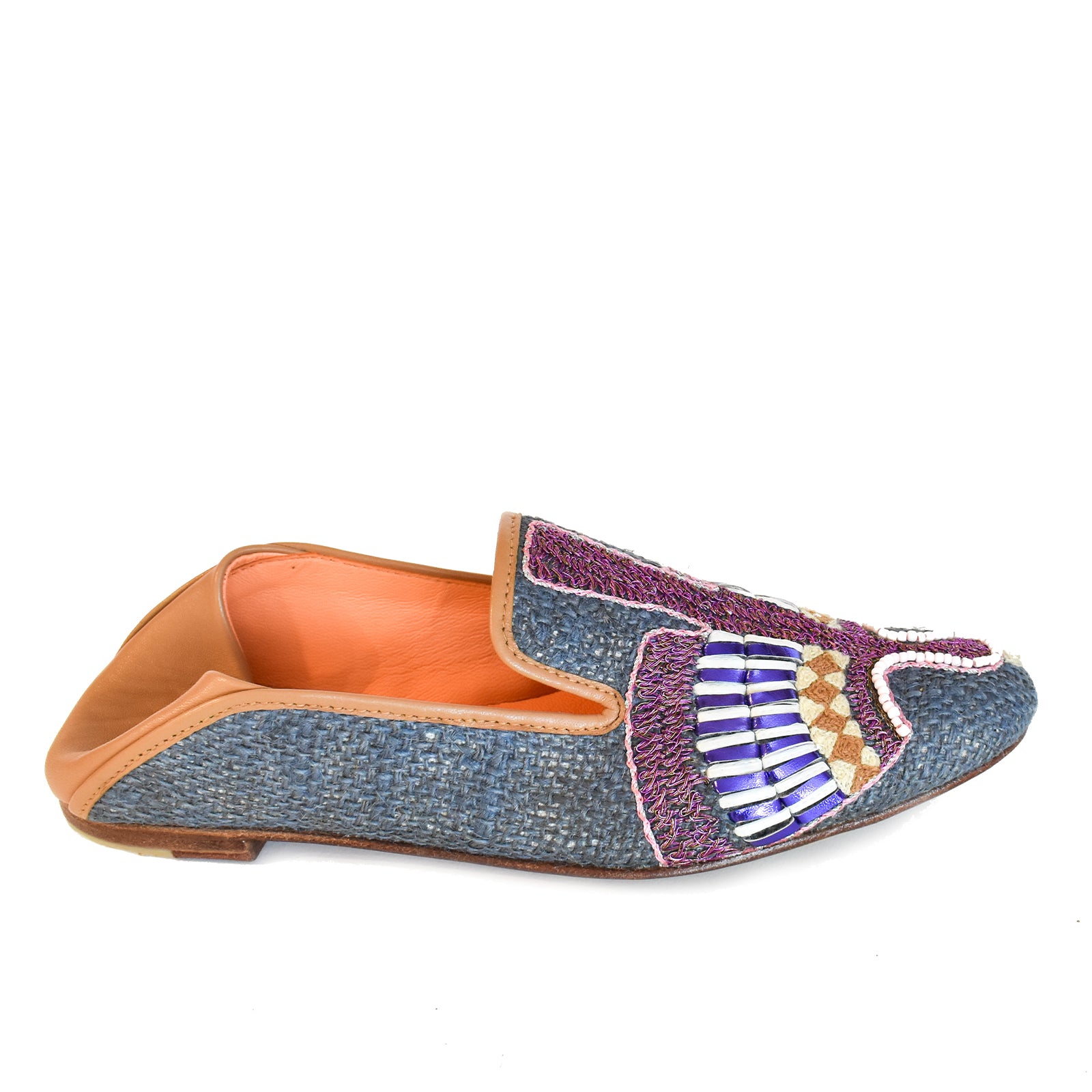Introducing the Anzu Moccasin—a blue woven loafer with tan leather lining and sole, showcasing intricate purple, white, gold, and blue beaded embroidery on the upper. This hand-embroidered leather moccasin is perfect for making a stylish statement.