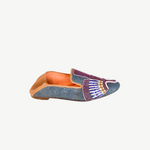 Introducing the Anzu Moccasin—a blue woven loafer with tan leather lining and sole, showcasing intricate purple, white, gold, and blue beaded embroidery on the upper. This hand-embroidered leather moccasin is perfect for making a stylish statement.