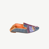 Introducing the Anzu Moccasin—a blue woven loafer with tan leather lining and sole, showcasing intricate purple, white, gold, and blue beaded embroidery on the upper. This hand-embroidered leather moccasin is perfect for making a stylish statement.