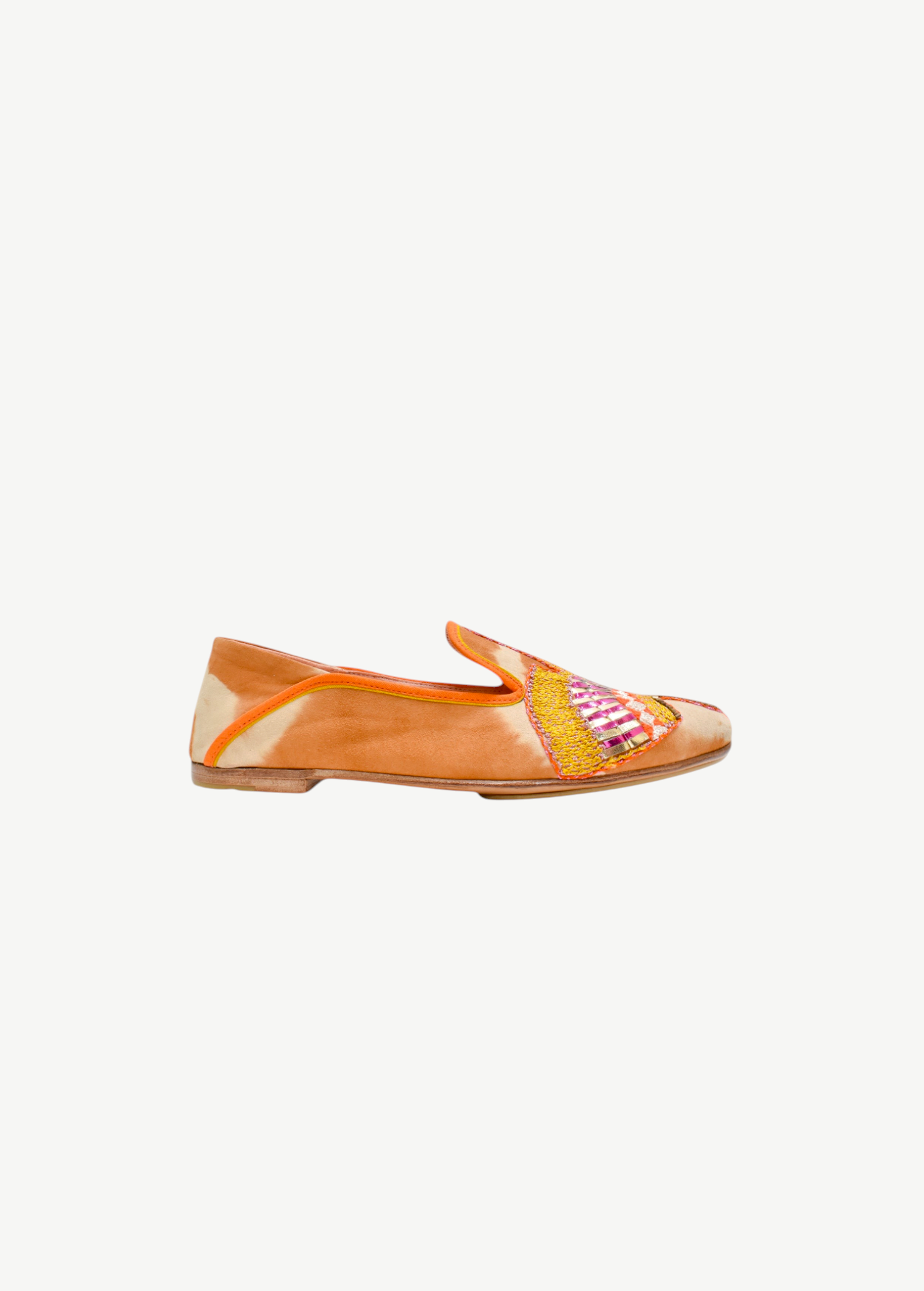The Anzu Moccasin is a brown and beige slip-on flat shoe with orange trim, showcasing a vibrant hand-embroidered moccasin design highlighted by yellow, pink, and gold accents on the side.
