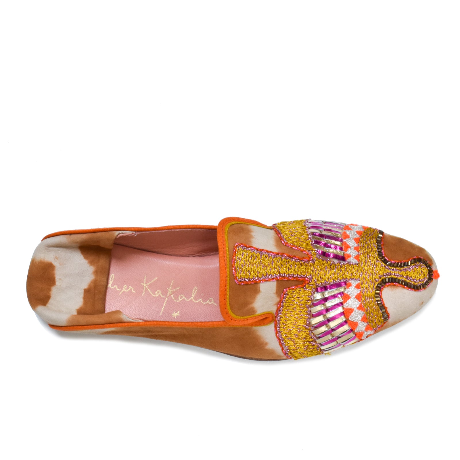 The Anzu Moccasin is a vibrant, hand-embroidered shoe crafted from tie dye leather in orange, brown, and white patches. It features intricate bead and thread embroidery of a bird on the top, and includes a pink insole embellished with gold text for an added touch of elegance. This sustainable moccasin combines artistry with eco-friendly craftsmanship.