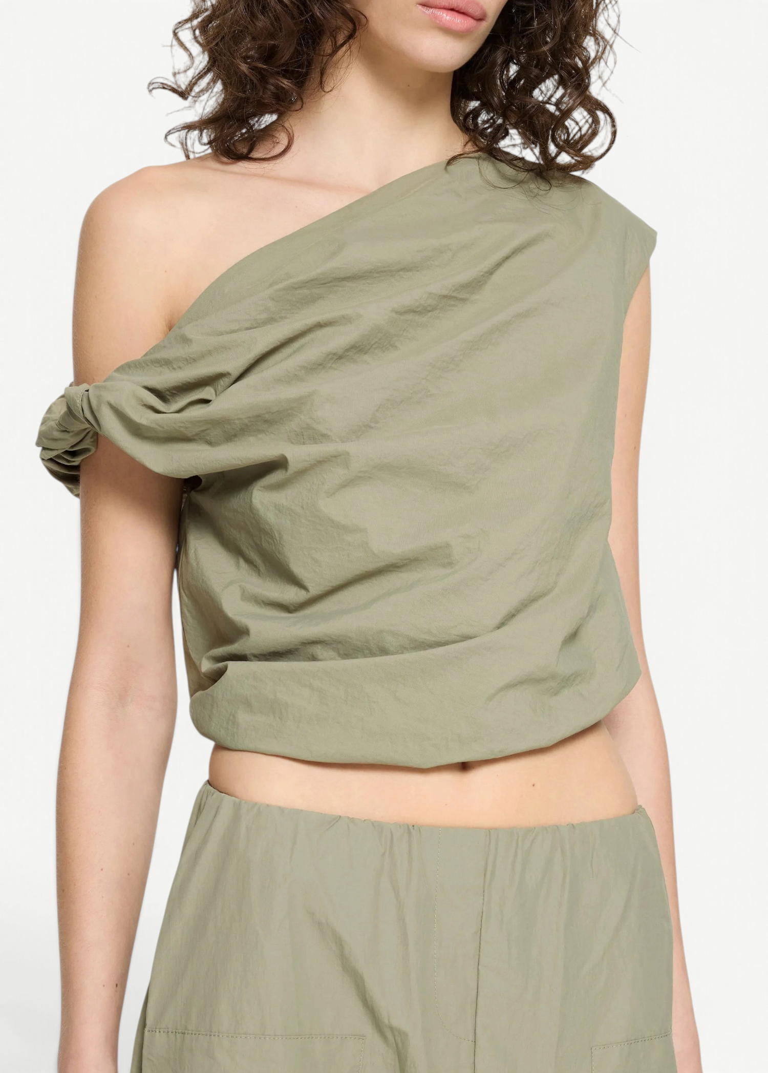 Alice Top in sage green, an asymmetric one-shoulder sleeveless crop top with a gathered, knotted detail at the shoulder for a sculptural finish.