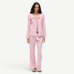 Model wearing KABE SHOP INC Malaika pants in light pink with a matching textured long-sleeve button-up shirt