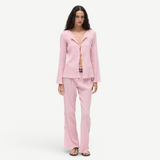 Model wearing KABE SHOP INC Malaika pants in light pink with a matching textured long-sleeve button-up shirt