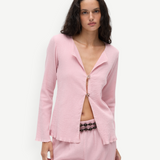 KABE SHOP INC Malaika Top in light pink with a textured finish, long sleeves, and decorative oversized buttons.