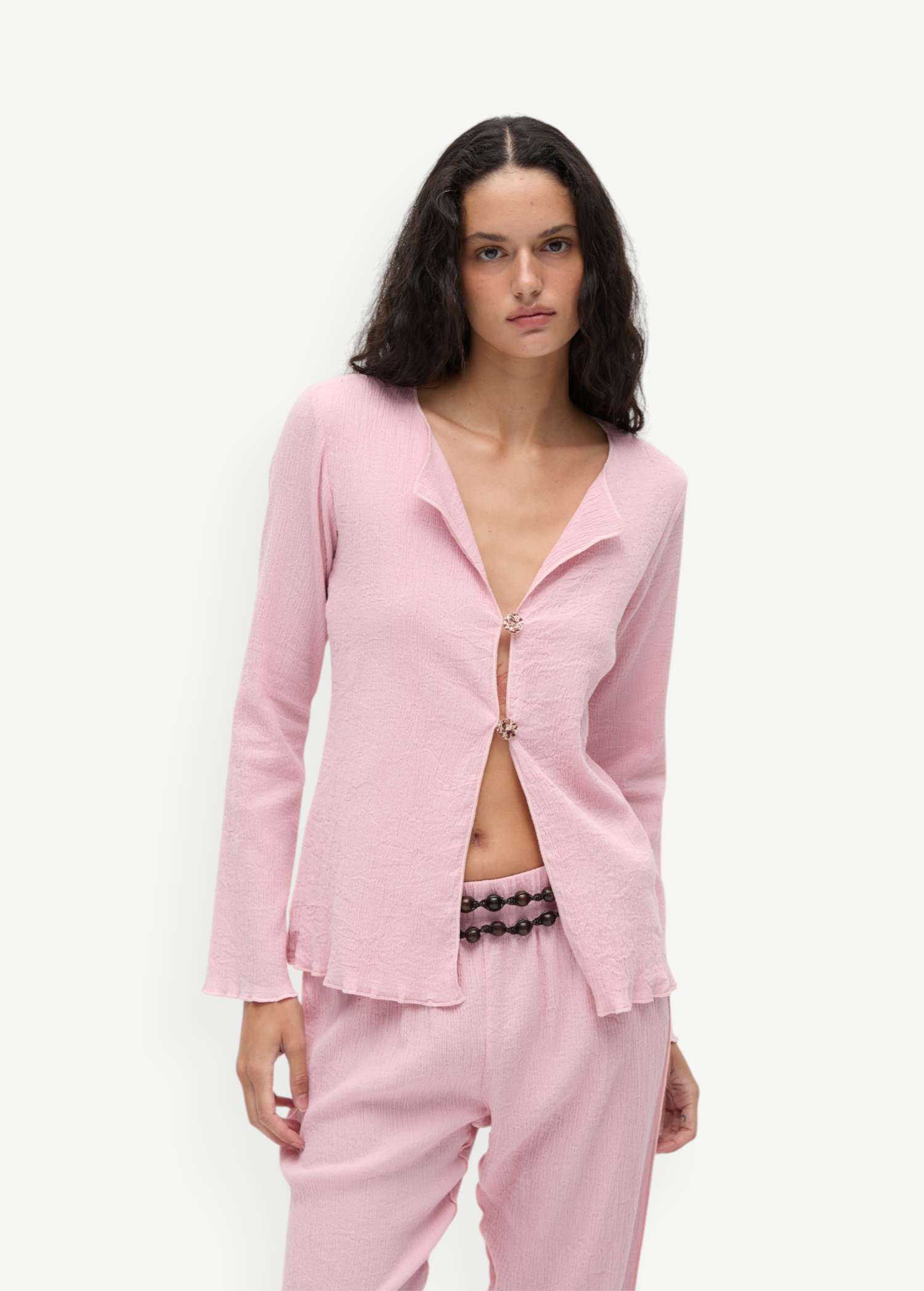 KABE SHOP INC Malaika Top in light pink with a textured finish, long sleeves, and decorative oversized buttons.