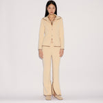 A model wears the light yellow Iris Top and matching flared trousers featuring a relaxed silhouette and visible dark stitched edges.