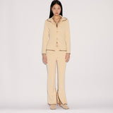 A model wears the light yellow Iris Top and matching flared trousers featuring a relaxed silhouette and visible dark stitched edges.