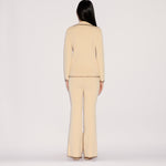 Back view of a person in a relaxed silhouette wearing a cream-colored Iris Top and matching flared trousers, both finished with decorative brown whipstitching along the hems and edges.