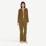Model wearing KABE SHOP INC Malaika olive green straight-leg pants with contrast white stitching and matching jacket.