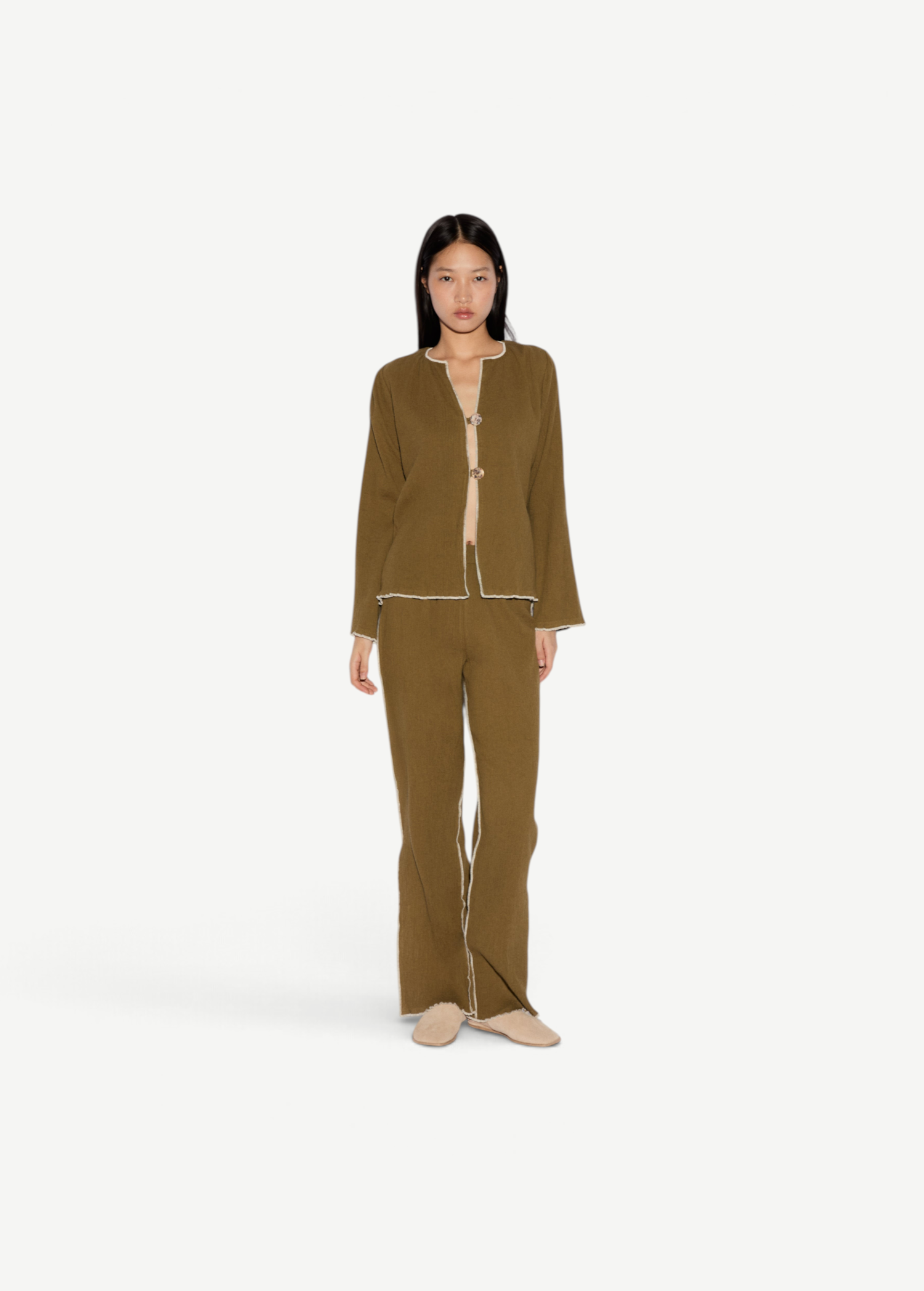 Model wearing KABE SHOP INC Malaika olive green straight-leg pants with contrast white stitching and matching jacket.