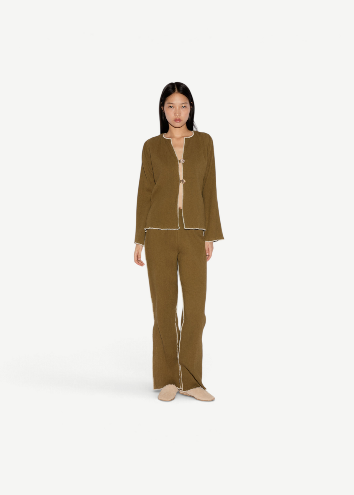 Model wearing KABE SHOP INC Malaika olive green straight-leg pants with contrast white stitching and matching jacket.