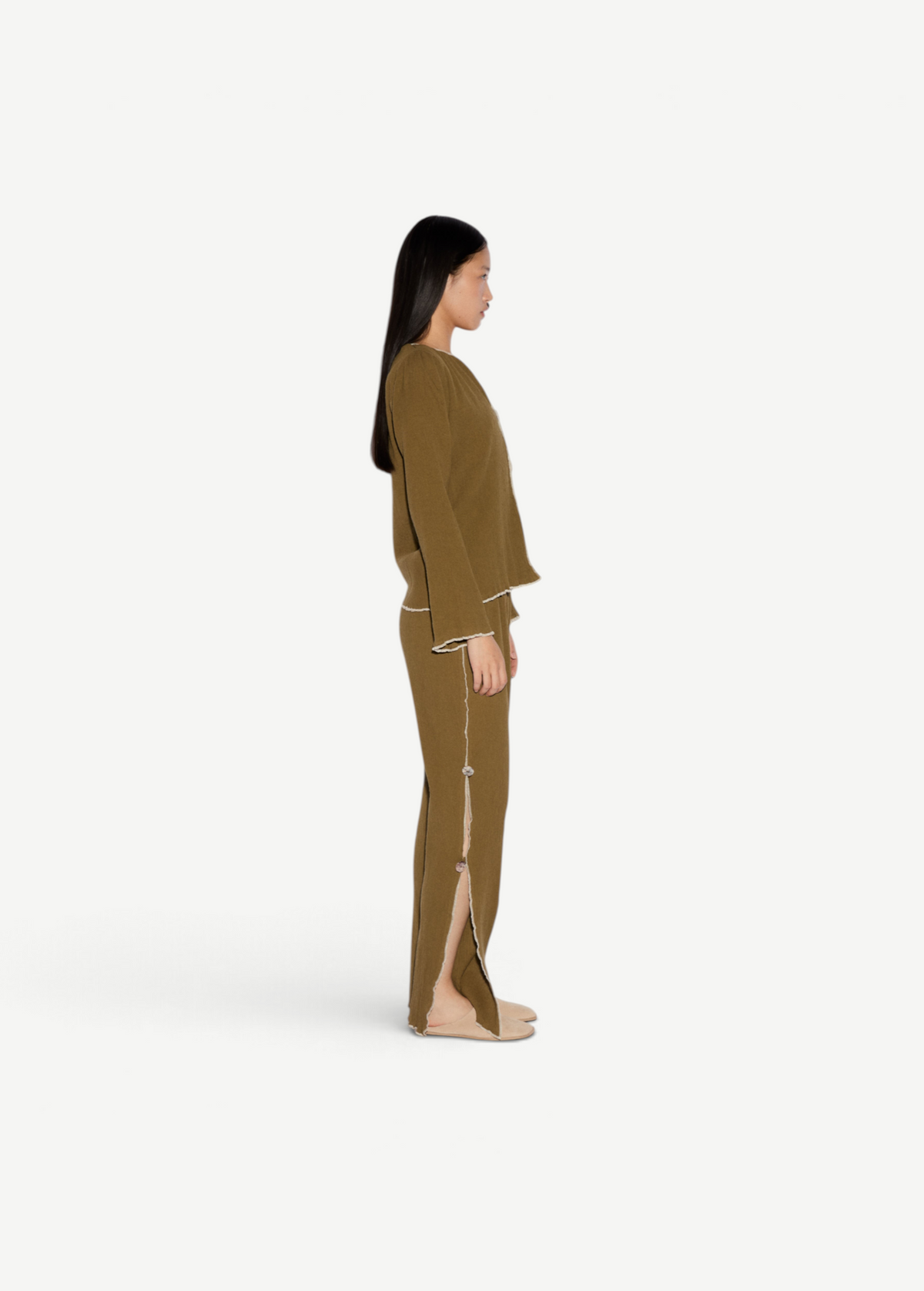 Model wearing KABE SHOP INC Malaika olive green straight-leg pants with side slit and contrast stitching