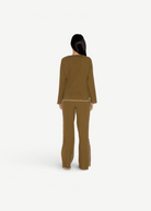 Back view of a woman wearing KABE SHOP INC Malaika Pants in olive green with contrast stitching and straight-leg fit.