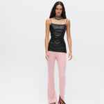A model wears a black spaghetti strap Xena Top with light pink ribbed flared trousers featuring hem slits, creating a body-hugging silhouette.
