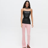 A model wears a black spaghetti strap Xena Top with light pink ribbed flared trousers featuring hem slits, creating a body-hugging silhouette.
