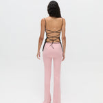 A body-hugging Xena Top with thin straps and a lace-up tie closure, paired with pink ribbed pants.