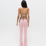 A body-hugging Xena Top with thin straps and a lace-up tie closure, paired with pink ribbed pants.