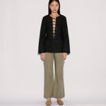 A model wearing a black long-sleeved top with a lace-up neckline and Sage Pants in a wide-leg silhouette.