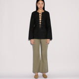 A model wearing a black long-sleeved top with a lace-up neckline and Sage Pants in a wide-leg silhouette.