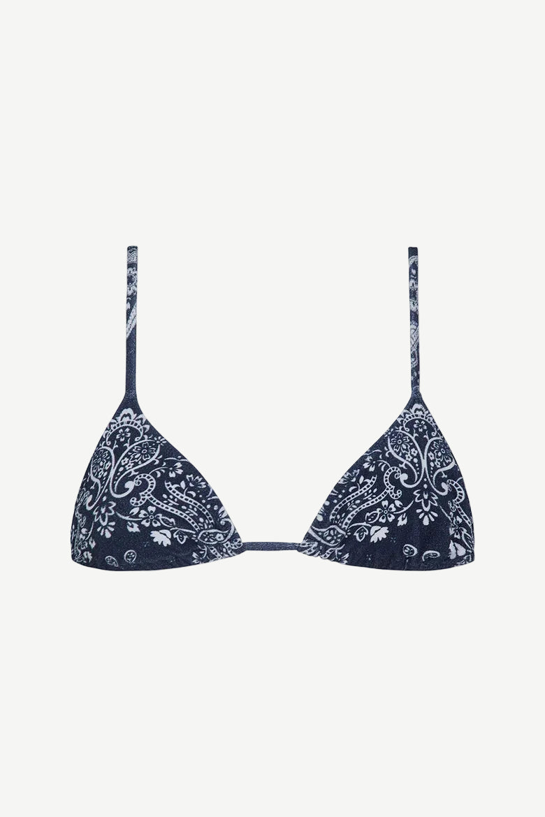 The Equator Top is a navy blue triangle bikini top with thin straps and a white paisley floral pattern. Made from ECONYL regenerated nylon, this adjustable bikini top offers a simple, minimalistic design for an effortlessly chic look.